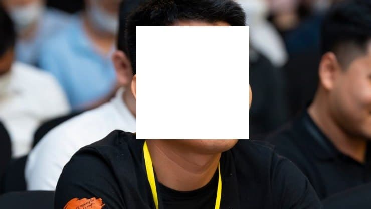Duc Tran seated at an industry conference, face redacted for privacy.